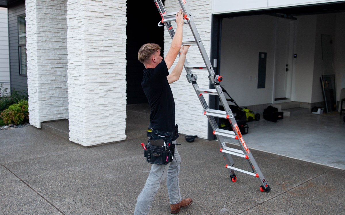 Sam Belza positioning a ladder for a residential roof inspection