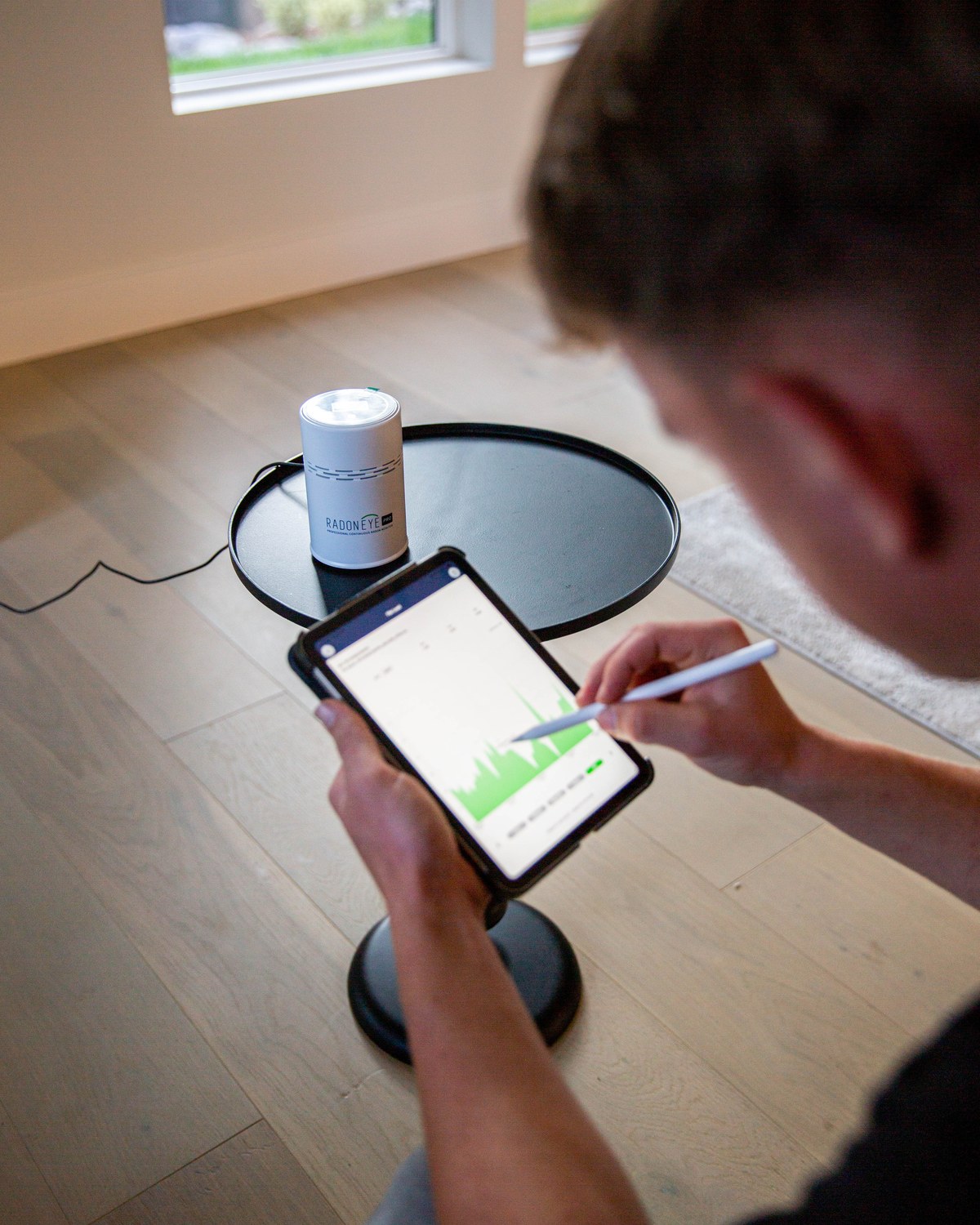 Sam Belza reviewing measured results beside a residential radon testing monitor