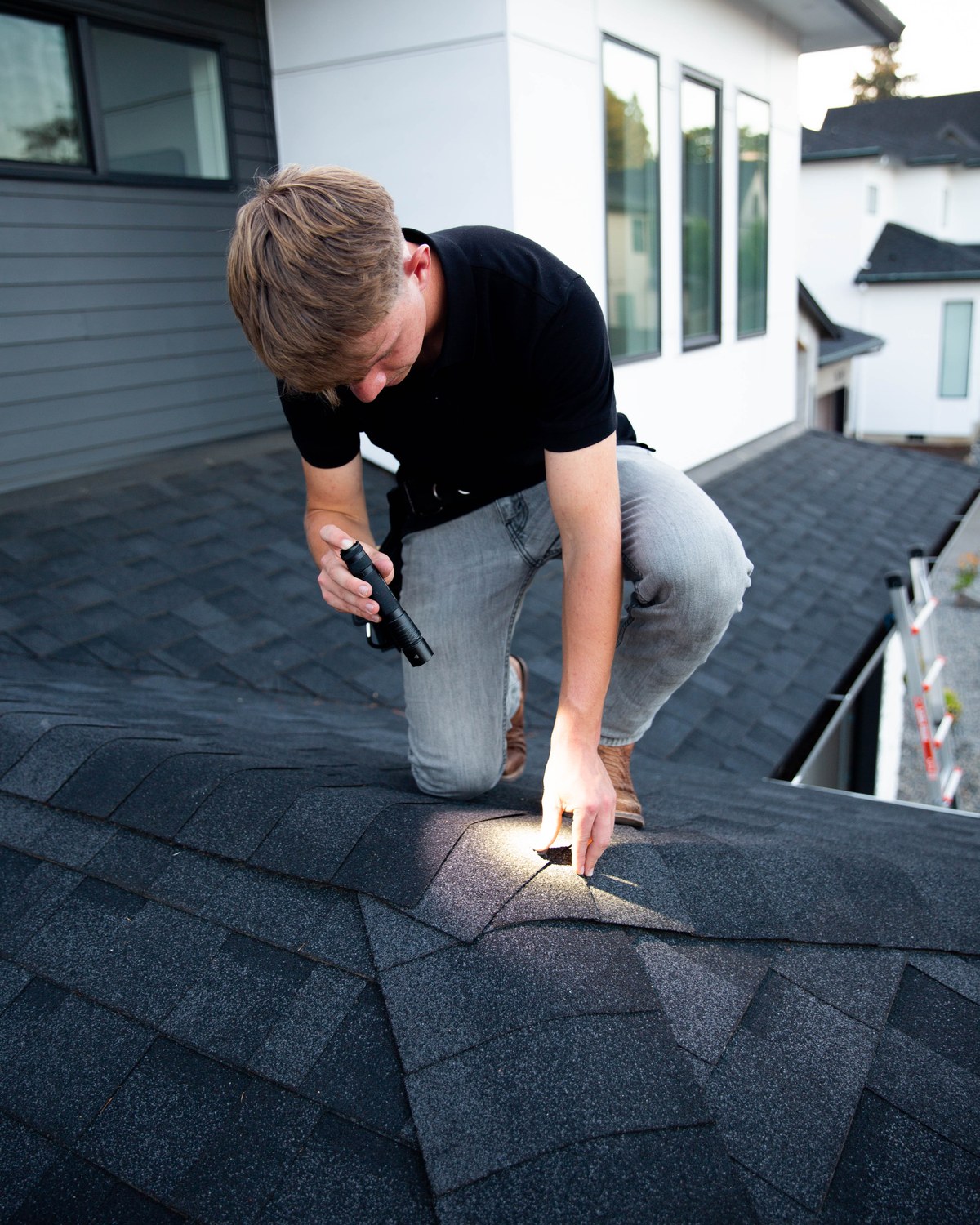 Sam Belza closely examining roof shingles during a pre-purchase home inspection